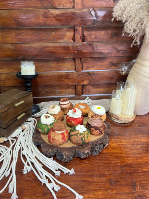 Nouă sortimente de choux prezentate pe un blat de lemn, decor marca Something Sweet
